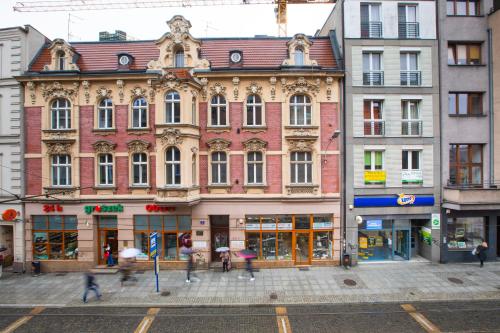 un edificio en una calle con gente caminando delante de él en Apartamenty Jana en Katowice