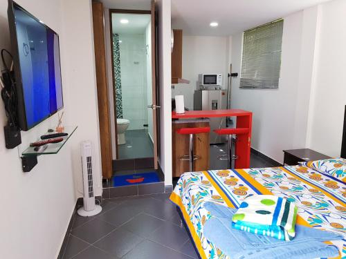 een slaapkamer met een bed, een bureau en een televisie bij New Cozy Apartment in the Poblado, San Lucas in Medellín