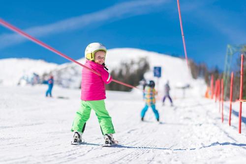 a young girl holding a pole on skis in the snow at Haus Bauer in Pertisau