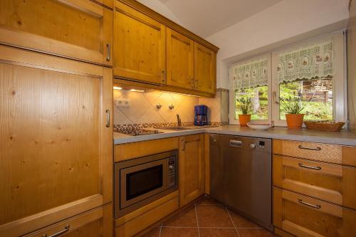 a kitchen with wooden cabinets and stainless steel appliances at Gästehaus Lärchenhang in Mittenwald