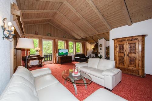 a living room with white couches and a television at Gästehaus Lärchenhang in Mittenwald