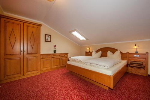 a bedroom with a bed and wooden cabinets at Gästehaus Lärchenhang in Mittenwald
