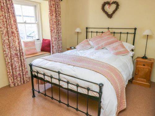 um quarto com uma cama com almofadas cor-de-rosa e brancas em Rose Cottage em Skipton