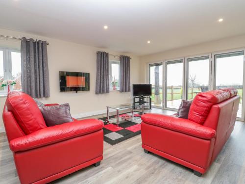 a living room with two red chairs and a television at The Donkey Shed in Sherborne