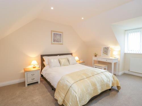 a bedroom with a bed and a desk with two lamps at The Donkey Shed in Sherborne