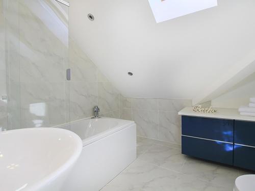 a white bathroom with a tub and a sink at Penmynydd in Trearddur