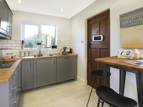 a kitchen with a sink and a counter with stools at Perthi in Morfa Nefyn