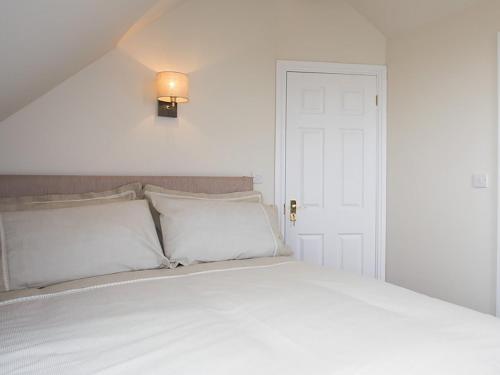 a bed with white sheets and a light above it at Pen Y Prys in Pentraeth