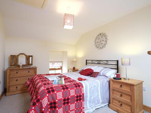 a bedroom with a bed with a red and white blanket at Pen Y Bont in Llandwrog