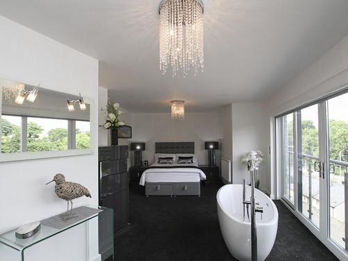 a bedroom with a bed and a tub and a chandelier at Quayside in Y Felinheli