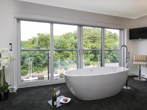 a white bath tub in a room with a large window at Quayside in Y Felinheli