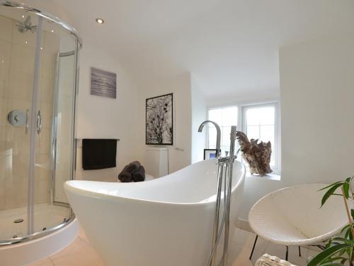 ein weißes Badezimmer mit Badewanne und Dusche in der Unterkunft Rhianfa Cottage in Menai Bridge