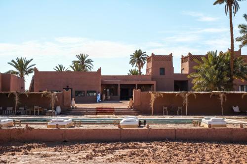 a building in the middle of a desert with palm trees at Kasbah Aitisfoul in Tagounite