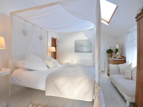ein Schlafzimmer mit einem weißen Himmelbett und einer Couch in der Unterkunft Rhianfa Cottage in Menai Bridge