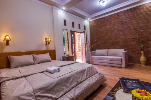 a bedroom with a large bed and a brick wall at Maher House Borobudur in Magelang