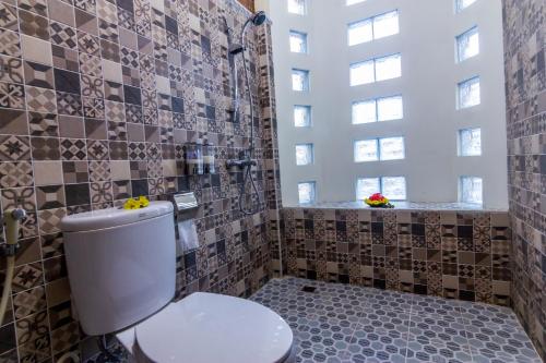 a bathroom with a toilet and a tiled wall at Maher House Borobudur in Magelang