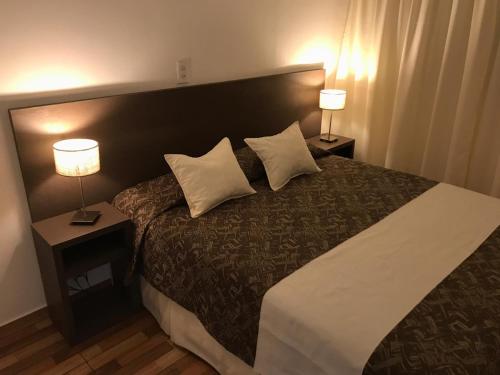 a hotel room with a large bed with two lamps at Bagu Playa Grande Hotel in Mar del Plata