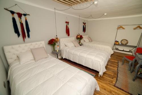 two beds in a room with white sheets at Home Garden Hotel in Cusco