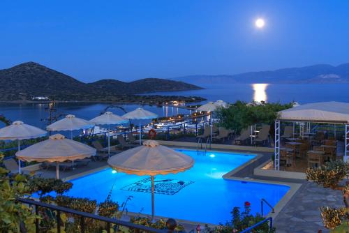a view of a pool at night with umbrellas at Elounda Heights (Adults Only) in Elounda
