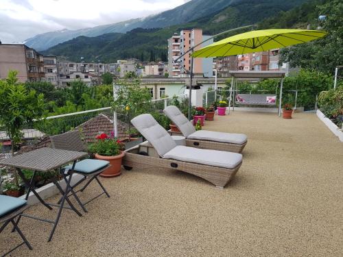 a patio with two chairs and a yellow umbrella at Ilir Guest House 1 in Përmet