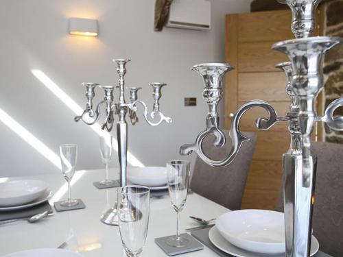una mesa blanca con vasos y cubiertos. en Rhyd Angharad Barns en Llanrhyddlad