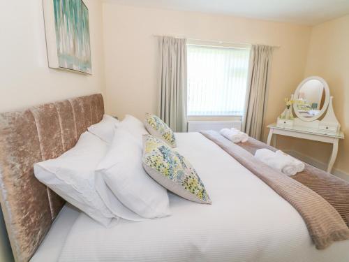 ein Schlafzimmer mit einem Bett mit Kissen und einem Spiegel in der Unterkunft Llain Bach in Llangefni