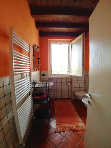 an orange bathroom with a toilet and a window at Haus Colà in Colà di Lazise