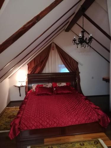 a bedroom with a red bed with a chandelier at Vila Kraljica Vrdnik in Vrdnik