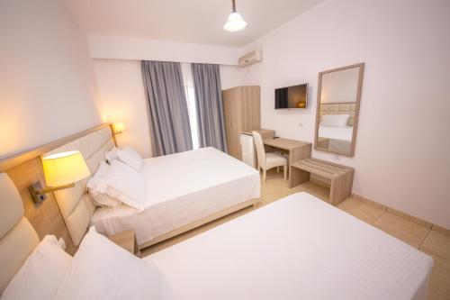 a hotel room with two beds and a desk at Hotel Alina in Sarandë