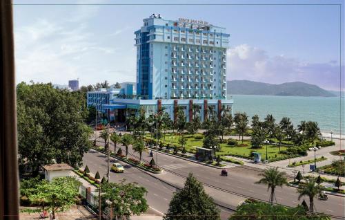 a large blue building with a road in front of the ocean at My Hotel in Quy Nhon