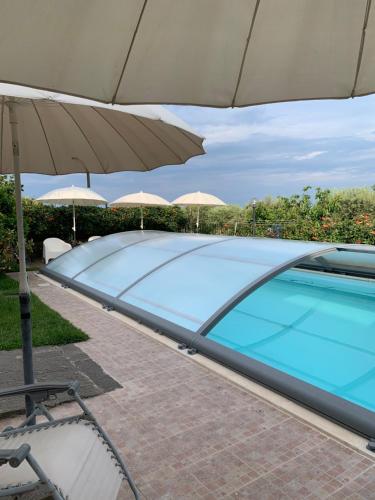 a swimming pool with an umbrella and a chair and a table at Villa Tranquilla in Riposto