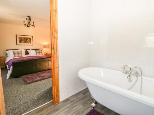 a bathroom with a bath tub and a bedroom at Willow Lodge in Brough