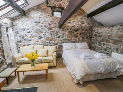 um quarto com uma cama e uma parede de pedra em Waterfall Cottage em Caernarfon