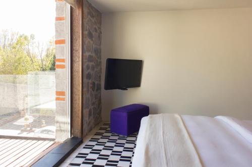 una camera con letto e TV a parete di La Purificadora, Puebla, a Member of Design Hotels a Puebla