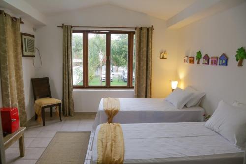 a hotel room with two beds and a window at Yucca Pousada in Arraial d'Ajuda