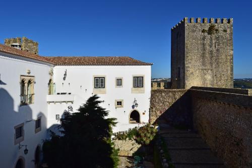 a white building with a tower and a castle at Pousada Castelo de Obidos in Óbidos