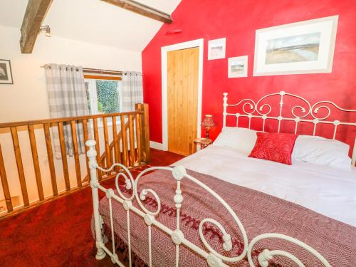 a bedroom with a red wall with a bed in it at Little Bargate in Castleton