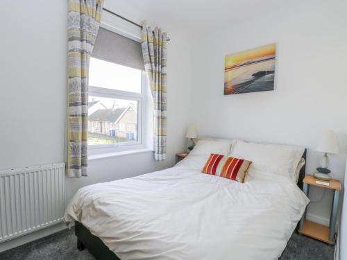 a bedroom with a white bed with a window at Sea Breakers Cottage in Filey