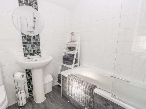 a bathroom with a white tub and a sink and a mirror at Sea Breakers Cottage in Filey