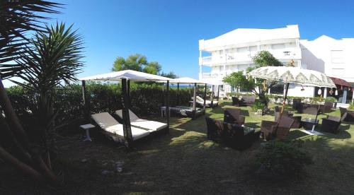 un groupe de chaises et de parasols dans une cour dans l'établissement Hotel Pineda Playa, à Noja
