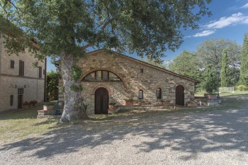 a brick building with a tree in front of it at Relais Santa Cristina in Radda in Chianti