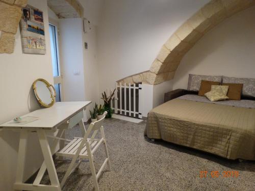 a bedroom with a bed and a desk with a mirror at La Casetta di Ninella in Polignano a Mare