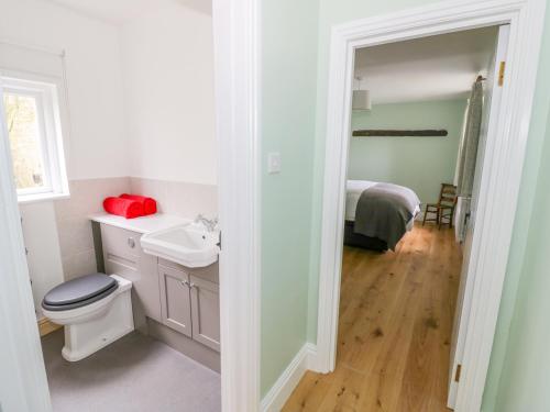 a white bathroom with a toilet and a sink at Wigrams Canalside Cottage in Southam