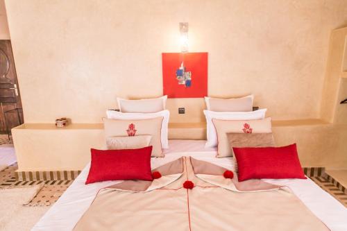 a room with three beds with red pillows at Riad Azawad in Merzouga