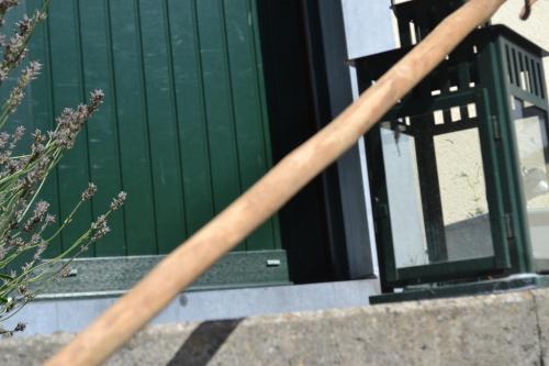 a wooden bat leaning against a green door at Gîte La Clef des Champs in Libin