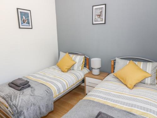 a bedroom with two beds with yellow pillows at 12 Keathbank Court in Blairgowrie