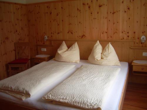 a bedroom with a bed with white sheets and pillows at Privatpension Gosaukammblick in Gosau