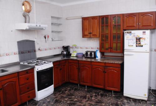 een keuken met houten kasten en een witte koelkast bij La Rojarilla in San Miguel de Tucumán