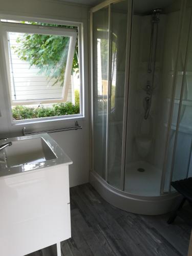 a bathroom with a shower and a sink and a window at Camping Loisirs Des Groux in Mousseaux-sur-Seine