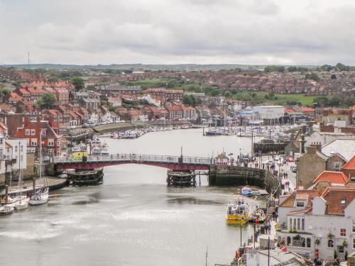 a river with a bridge and boats in a city at 5 Oystons Yard in Whitby
